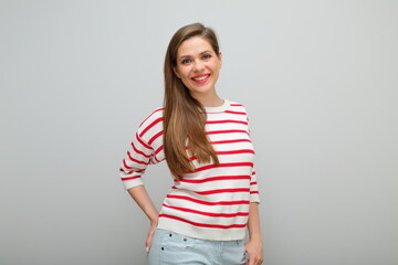 Smiling happy woman standing with hands in pockets, isolated female portrait, girl in white sweater with red stripes, young lady with long hair.