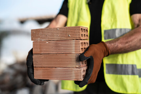 Anonymous construction worker carrying bricks