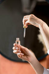  A woman holds a dropper and dropper with a drop of moisturizing serum for face and body skin care. Skin care concept.