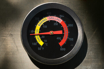 Grill thermometer on the brushed steel surface.