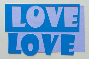 the word love (one a paper stencil) on lavender and gray paper