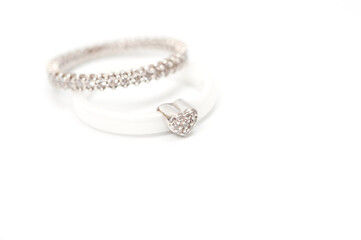 A white ceramic ring with a metal heart decorated with rhinestones and a silver ring with decorative stones.