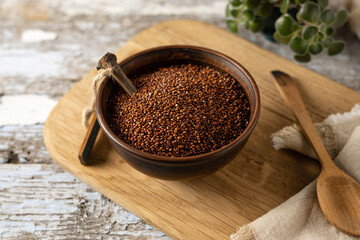 quinoa red dry, raw cereal in a bowl, cooking ingredient, wooden background