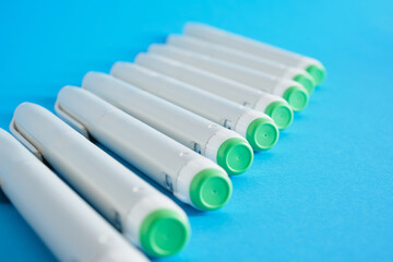 a lot of insulin syringe pens for diabetes treatment on blue background