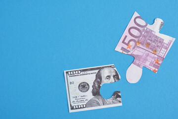 puzzles of euro bills and dollars on a blue background