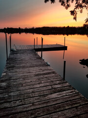 Fototapeta na wymiar Sunset on a calm Minnesota lake with wooden dock in foreground