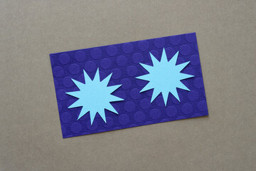 two blue paper starbursts on purple and beige