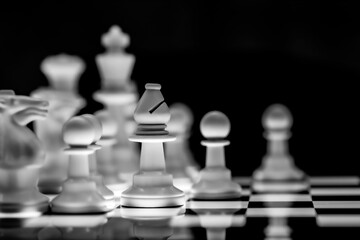 Close up of Chess pieces on a reflective mirror board surface with black background