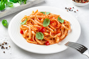 Classic Italian pasta with tomato sauce and basil on a light background close-up. Side view, close-up.