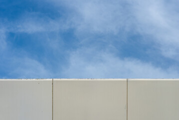Fototapeta na wymiar Abstract image, the corner of a modern building contrasting with the blue sky and soft white clouds.