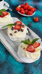 Pavlova meringue cakes with whipped cream and fresh strawberries, mint leaves. Selective focus.
