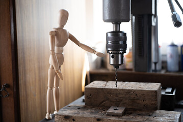 Close up of a wooden mannequin near a drill in the construction, rag doll