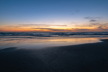 Twilight sky over the North Sea during the period of the shortest nights. Beautiful reflections of colours in the wet sand.