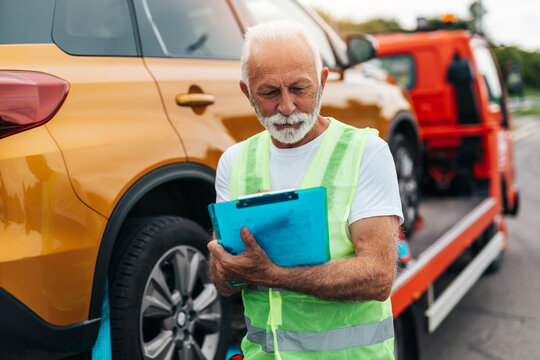 Handsome senior man working in towing service on the road. Roadside assistance concept.