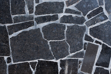 Black granite stone wall texture background with concrete white stripes