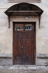 Old simple wooden door in a yellow brick wall with a lamp