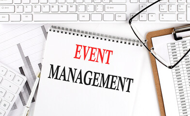 Text EVENT MANAGEMENT on Office desk table with keyboard, notepad and analysis chart on white background.