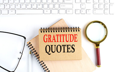 GRATITUDE QUOTES text in the office notebook with keyboard, magnifier and glasses , business concept