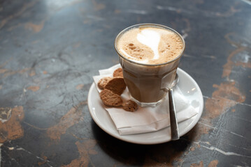 Coffee Cortado (piccolo latte) in a glass with cookies on a plate
