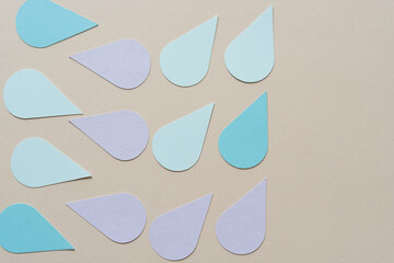 blue and violet paper petals or tear drops on beige paper