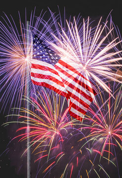 American flag on flagpole against fireworks