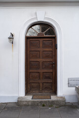 Wooden door with arch in old stone white house. Poland, Warsaw.