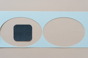 two oval shapes cut from a strip of blue paper and a blue square with rounded corners
