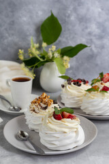 Pavlova meringue cakes with whipped cream and fresh strawberries, mint leaves. Selective focus.
