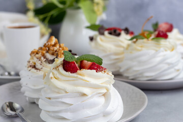 Pavlova meringue cakes with whipped cream and fresh strawberries, mint leaves. Selective focus.