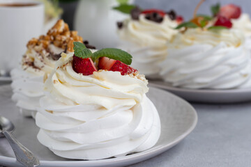 Pavlova meringue cakes with whipped cream and fresh strawberries, mint leaves. Selective focus.
