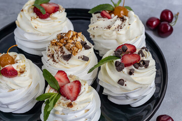Pavlova meringue cakes with whipped cream and fresh strawberries, mint leaves. Selective focus.
