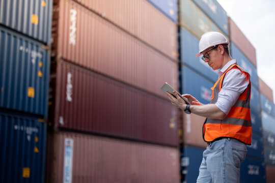 Container operator holding a tablet for his daily inspection of the container while walking in container yards.