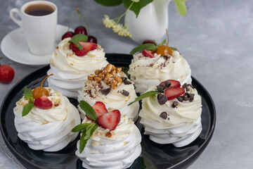Pavlova meringue cakes with whipped cream and fresh strawberries, mint leaves. Selective focus.