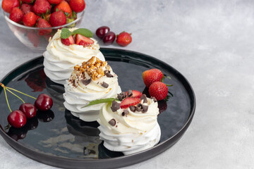 Pavlova meringue cakes with whipped cream and fresh strawberries, mint leaves. Selective focus.