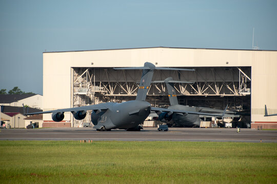 Two Boeing C-17 Globemasters parked at Charleston Air Force Base with one parked in a maintenance hangar