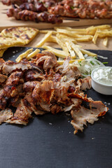 Greek gyro traditional meat food on black, overhead. Ethnic dish, meat cut, pita bread and tzatziki