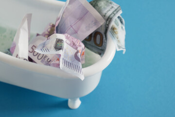 Fototapeta na wymiar euro and dollar bills in a small tub on a snowy background, foam on money, money laundering,