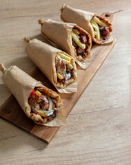 Gyro pita Shawarma wrap on wood table. Greek food with slice cut meat, overhead