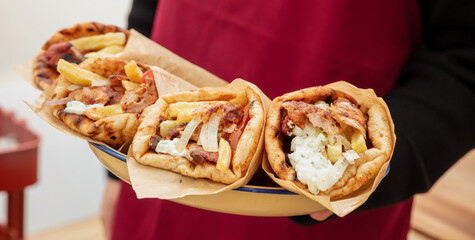 Gyro pita Shawarma, sliced meat tzatziki and vegetable wrap in male hand, close up view.