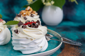 Pavlova meringue cakes with whipped cream and fresh strawberries, mint leaves. Selective focus.