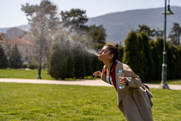 Young girl spitting water out from her mouth - obrazy, fototapety, plakaty
