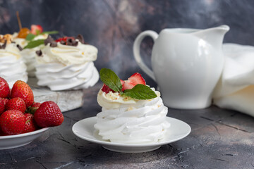 Pavlova meringue cakes with whipped cream and fresh strawberries, mint leaves. Selective focus.
