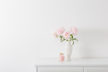 pink peonies in ceramic white vase in white interior