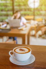 The ceramic cup of hot coffee in coffee shop or cafeteria with people. 