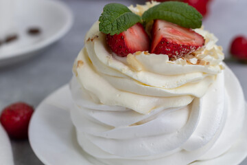 Pavlova meringue cakes with whipped cream and fresh strawberries, mint leaves. Selective focus.