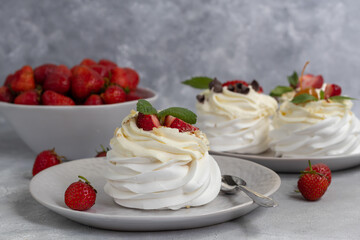Pavlova meringue cakes with whipped cream and fresh strawberries, mint leaves. Selective focus.