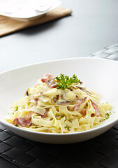 Close-up of pasta with cheese and bacon on wooden table