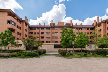 Facades of urban residential buildings with trees, sand and blue sky with clouds