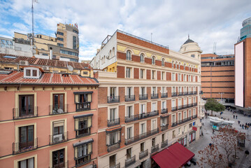 Fototapeta premium Facades of old urban residential buildings with clay roofs and small attic windows near Plaza del Callao in Madrid