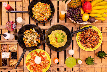 Set of large pans full of salads, plates with salads, snacks of nuts and chocolate and tomato and burrata salad